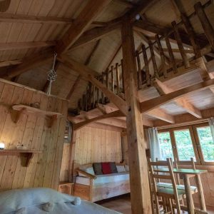 Cabane en bois chaleureuse avec mezzanine et lumière naturelle à Auvergne-Rhône-Alpes.