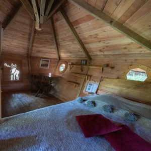 Cabane en bois avec intérieur chaleureux et fenêtres octogonales. Parfait pour un séjour unique.
