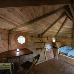 Cabane en bois avec fenêtres octogonales, offrant une ambiance chaleureuse et naturelle.
