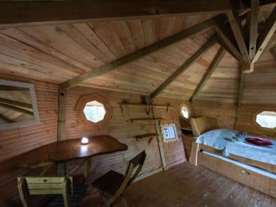Cabane en bois avec fenêtres octogonales, offrant une ambiance chaleureuse et naturelle.