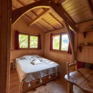 Chalet en bois chaleureux avec lit douillet et vue sur la nature environnante.