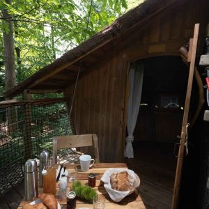Cabane dans les arbres en Auvergne, avec petit-déjeuner sur une table en bois.