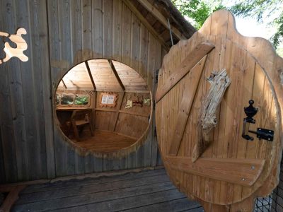 Cabane en bois ronde avec une porte originale et un intérieur chaleureux.