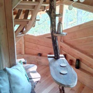 Cabane perchée en bois avec une table originale et vue sur la nature environnante.