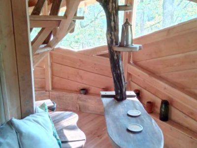 Cabane perchée en bois avec une table originale et vue sur la nature environnante.