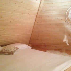 Chalet en bois cosy avec lit douillet et décorations en macramé.