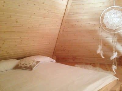 Chalet en bois cosy avec lit douillet et décorations en macramé.
