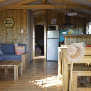 Cabane en bois moderne avec salon lumineux et cuisine ouverte, décorée avec des touches colorées.