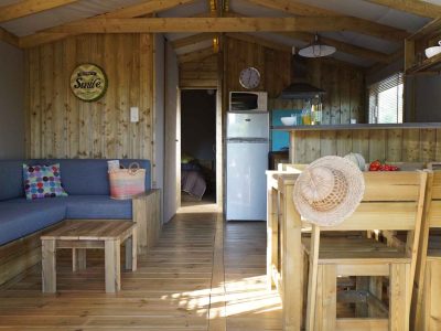 Cabane en bois moderne avec salon lumineux et cuisine ouverte, décorée avec des touches colorées.