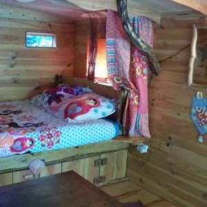 Cabane en bois colorée avec lit douillet et décor chaleureux en Basse-Normandie.