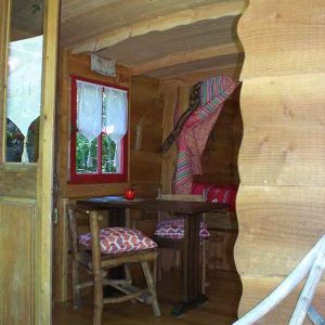 Cabane en bois à Basse-Normandie, avec une table en bambou et des coussins colorés.