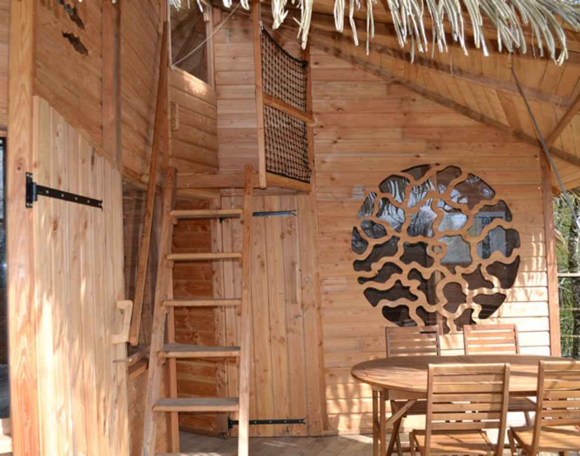 Cabane en bois avec toit en chaume, escaliers en bois et décorations originales.