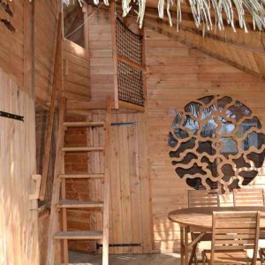 Cabane en bois avec toit en chaume, escaliers en bois et décorations originales.