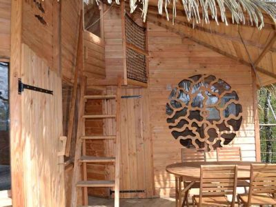 Cabane en bois avec toit en chaume, escaliers en bois et décorations originales.