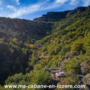 Cabane perchée dans les arbres, entourée de verdure et de montagnes majestueuses.