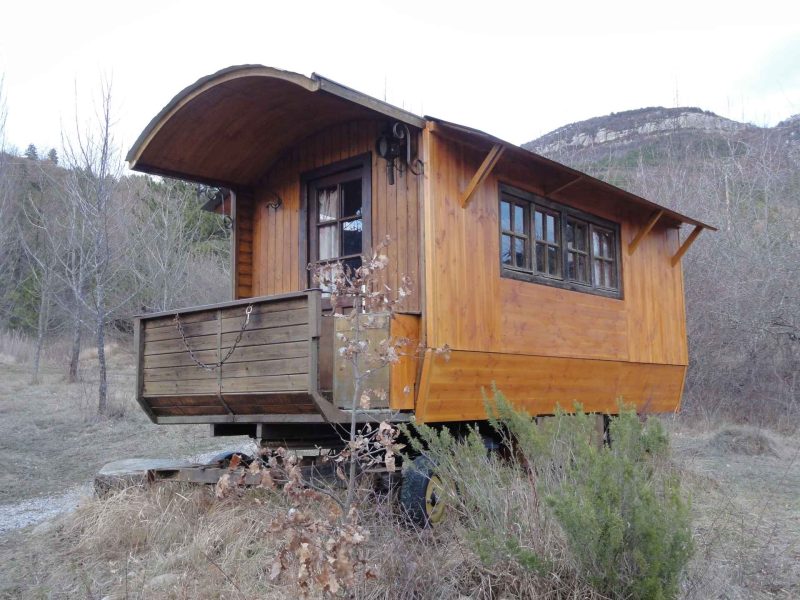Charmante roulotte en bois, nichée dans la nature, avec un balcon accueillant.