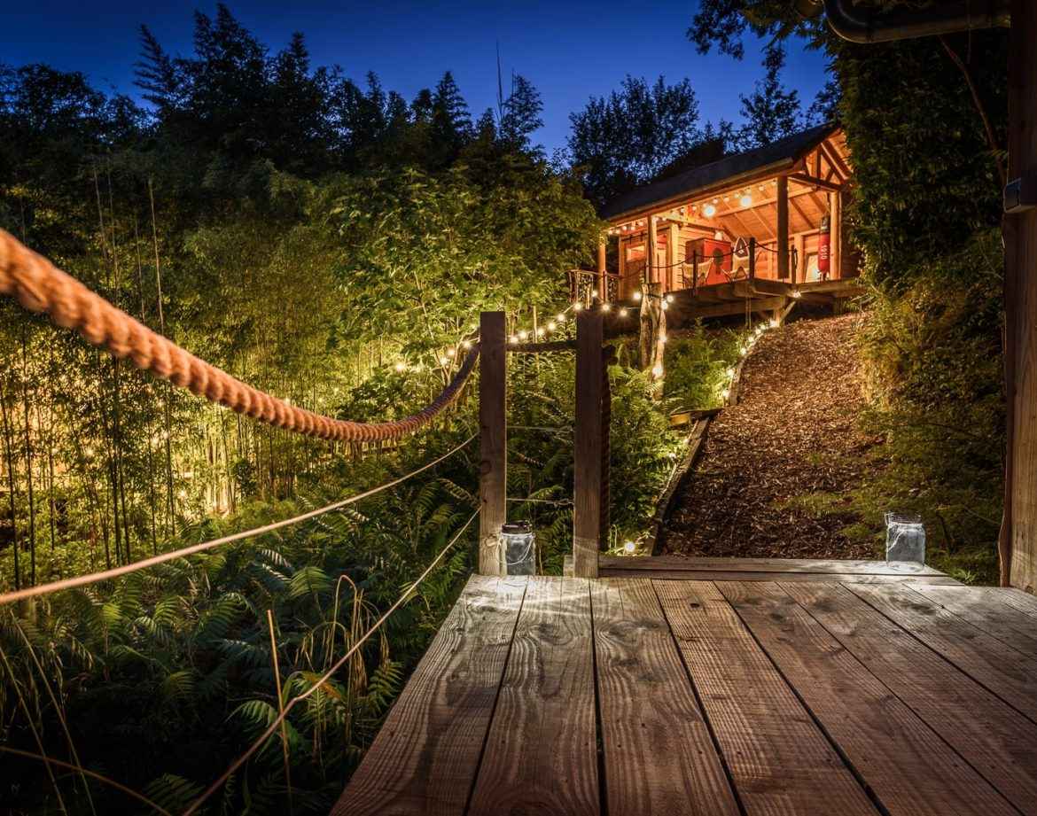 Cabane perchée en Aquitaine, éclairée par des guirlandes lumineuses.
