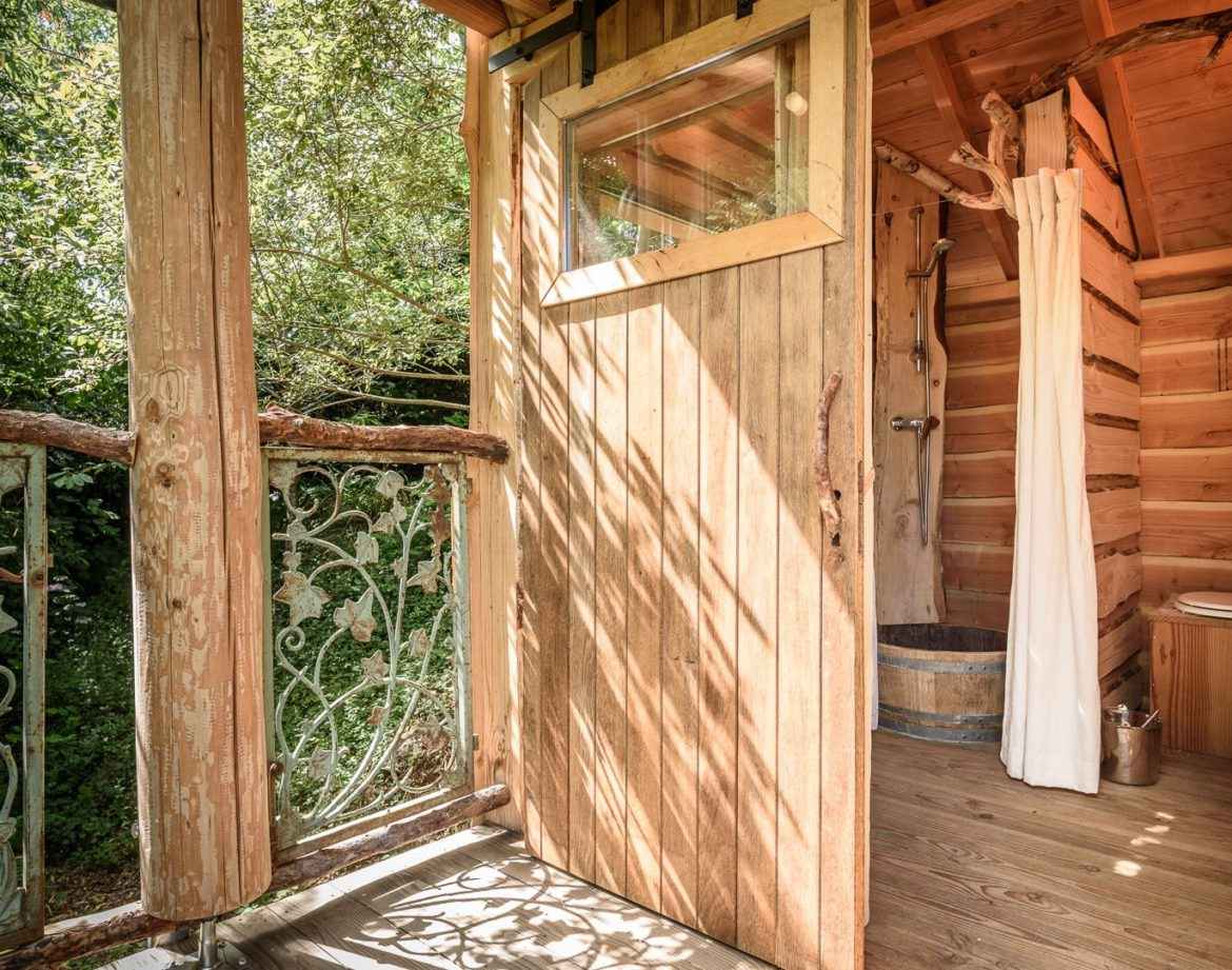 Cabane perchée en Aquitaine avec une salle de bain en bois et vue sur la nature.
