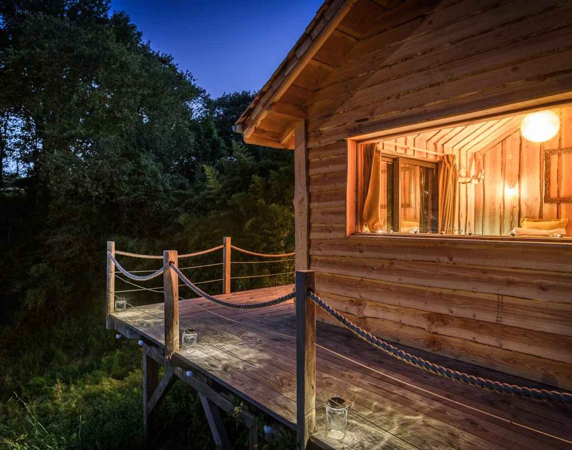 Cabane perchée en bois avec terrasse lumineuse, entourée de verdure en Aquitaine.