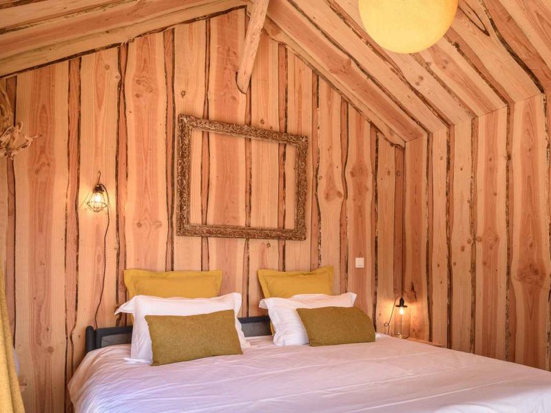 Chalet en bois chaleureux avec un lit double et des murs en bois naturel.