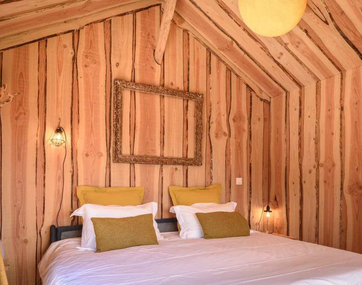 Chalet en bois chaleureux avec murs en pin et literie confortable en Aquitaine.