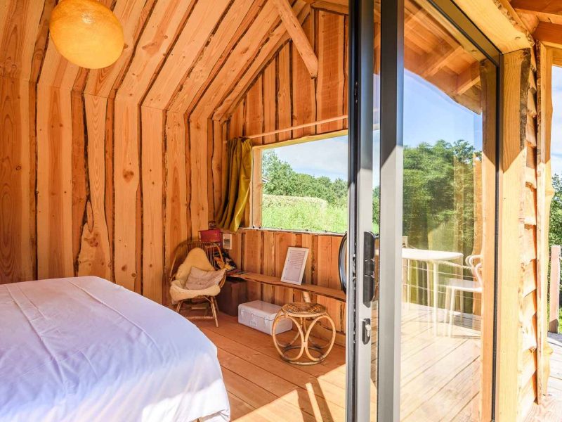 Chalet en bois chaleureux avec vue sur la nature et lumière naturelle abondante.