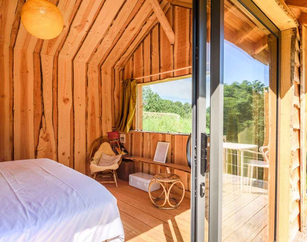 Cabane en bois avec vue sur la nature, ambiance chaleureuse et lumineuse.