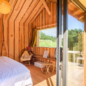 Cabane en bois avec vue sur la nature, ambiance chaleureuse et lumineuse.