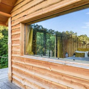 Cabane en bois avec grande fenêtre, offrant une vue sur la nature en Aquitaine.
