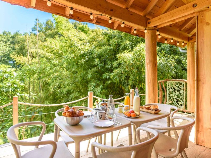 Chalet en bois avec terrasse, petit-déjeuner en plein air et vue verdoyante.
