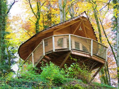 Cabane perchée en bois, entourée de feuillage automnal en Bourgogne-Franche-Comté.