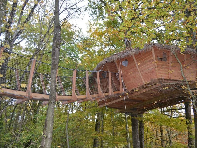 Cabane perchée dans les arbres, entourée de feuillage coloré en Pays de la Loire.