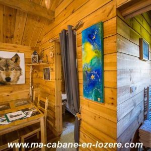 Cabane en bois chaleureuse avec décoration artistique et vue sur la nature.