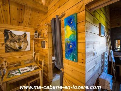 Cabane en bois chaleureuse avec décoration artistique et vue sur la nature.