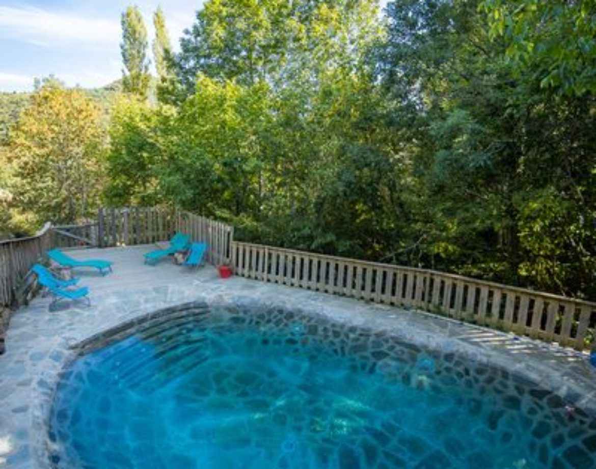 Cabane perchée en Languedoc-Roussillon avec piscine naturelle entourée de verdure.