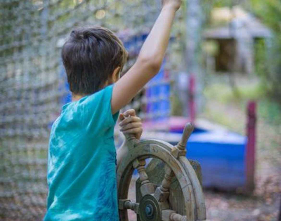 Enfant jouant avec un gouvernail dans un hébergement insolite en pleine nature.