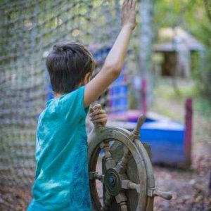 Enfant jouant avec un gouvernail dans un hébergement insolite en pleine nature.