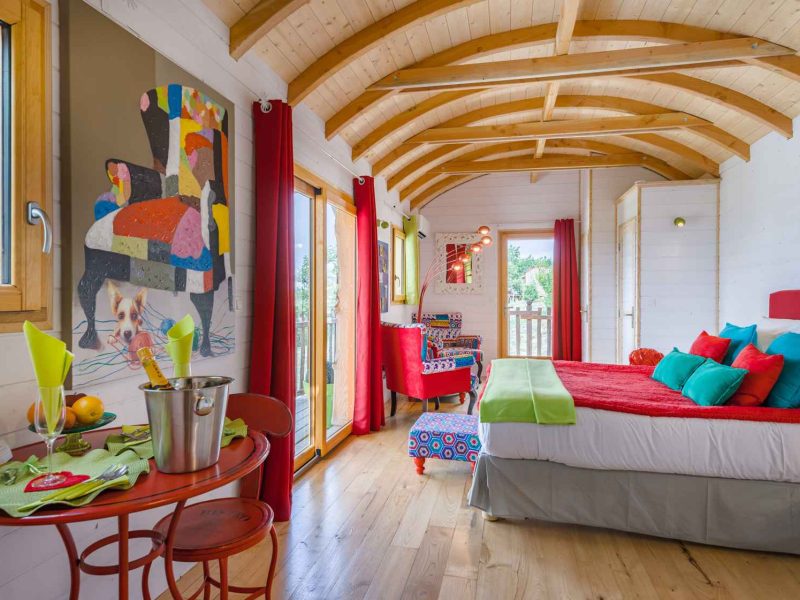 Chalet coloré avec un lit douillet et une vue sur la nature, ambiance chaleureuse.