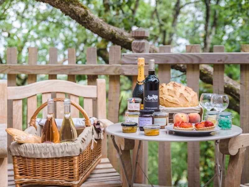 Terrasse dune cabane avec panier pique-nique, vin et douceurs locales.