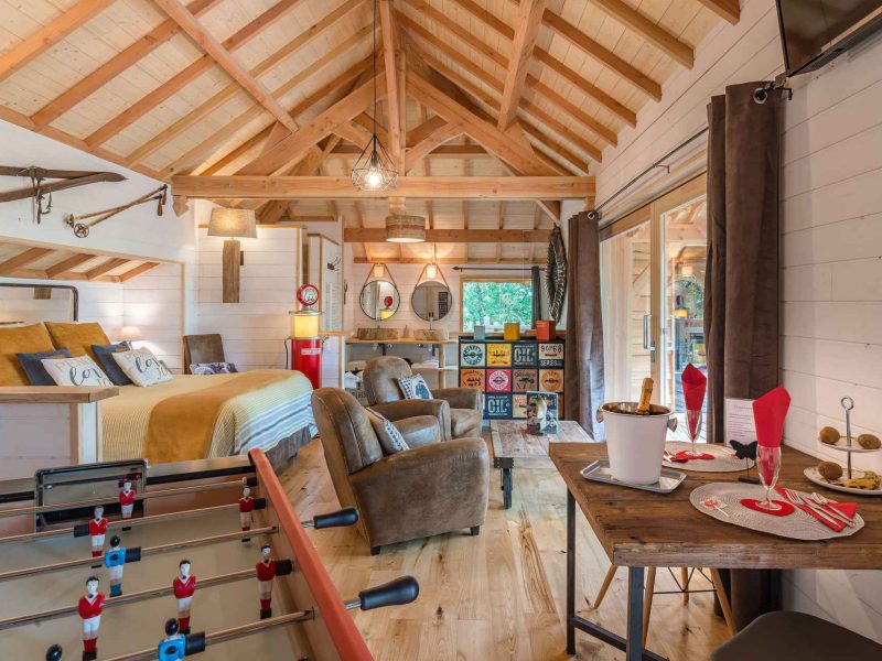 Chalet moderne avec un intérieur en bois, coin repas et table de baby-foot.