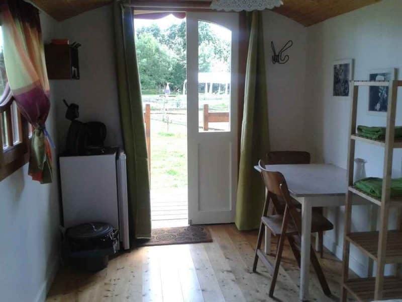 Charmante cabane avec vue sur la nature, équipée dune table et kitchenette.