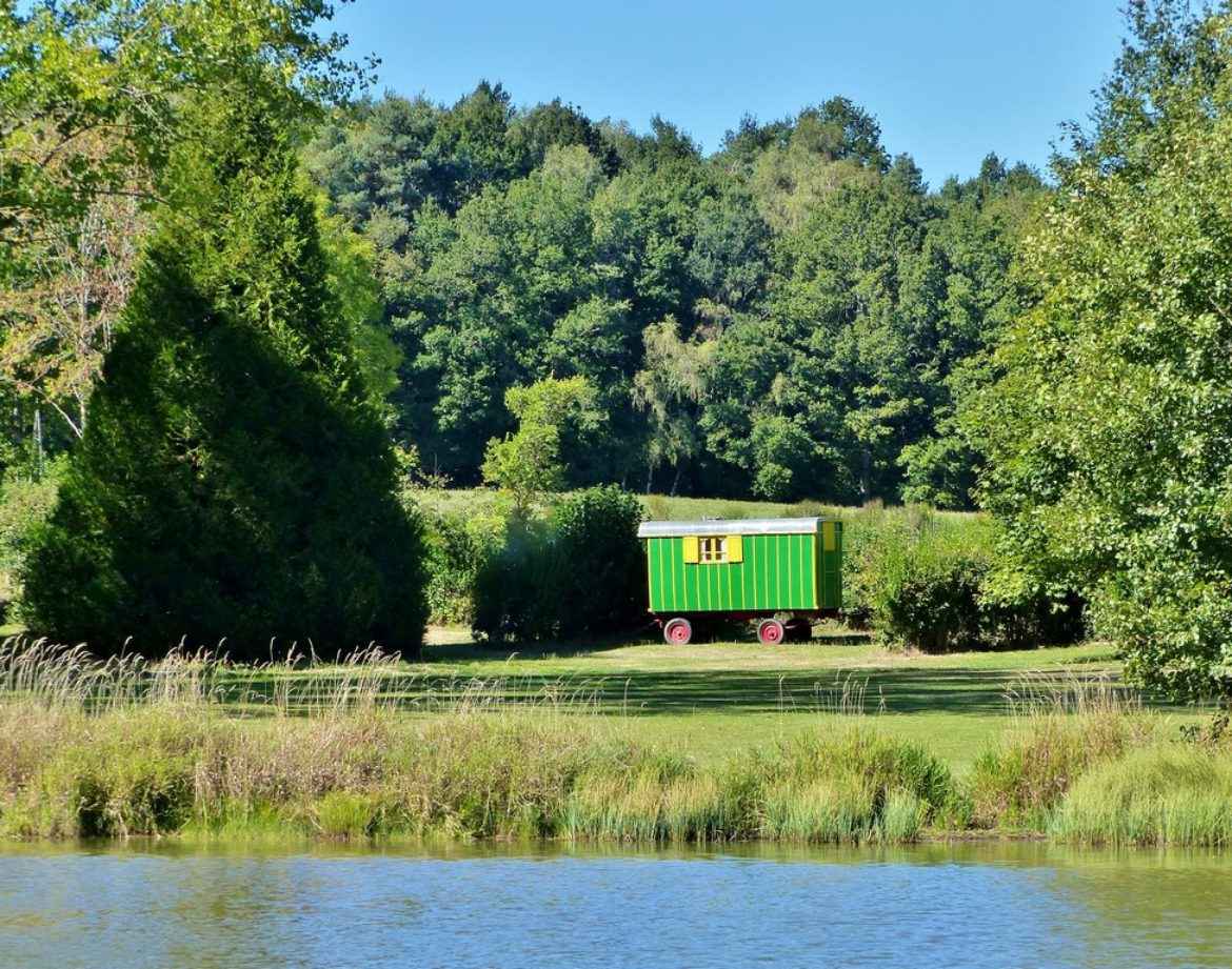 Roulotte colorée au bord dun lac, entourée de verdure en Auvergne.