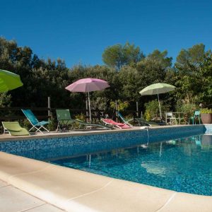 Hébergement insolite en Provence-Alpes-Côte dAzur avec piscine et parasols colorés.
