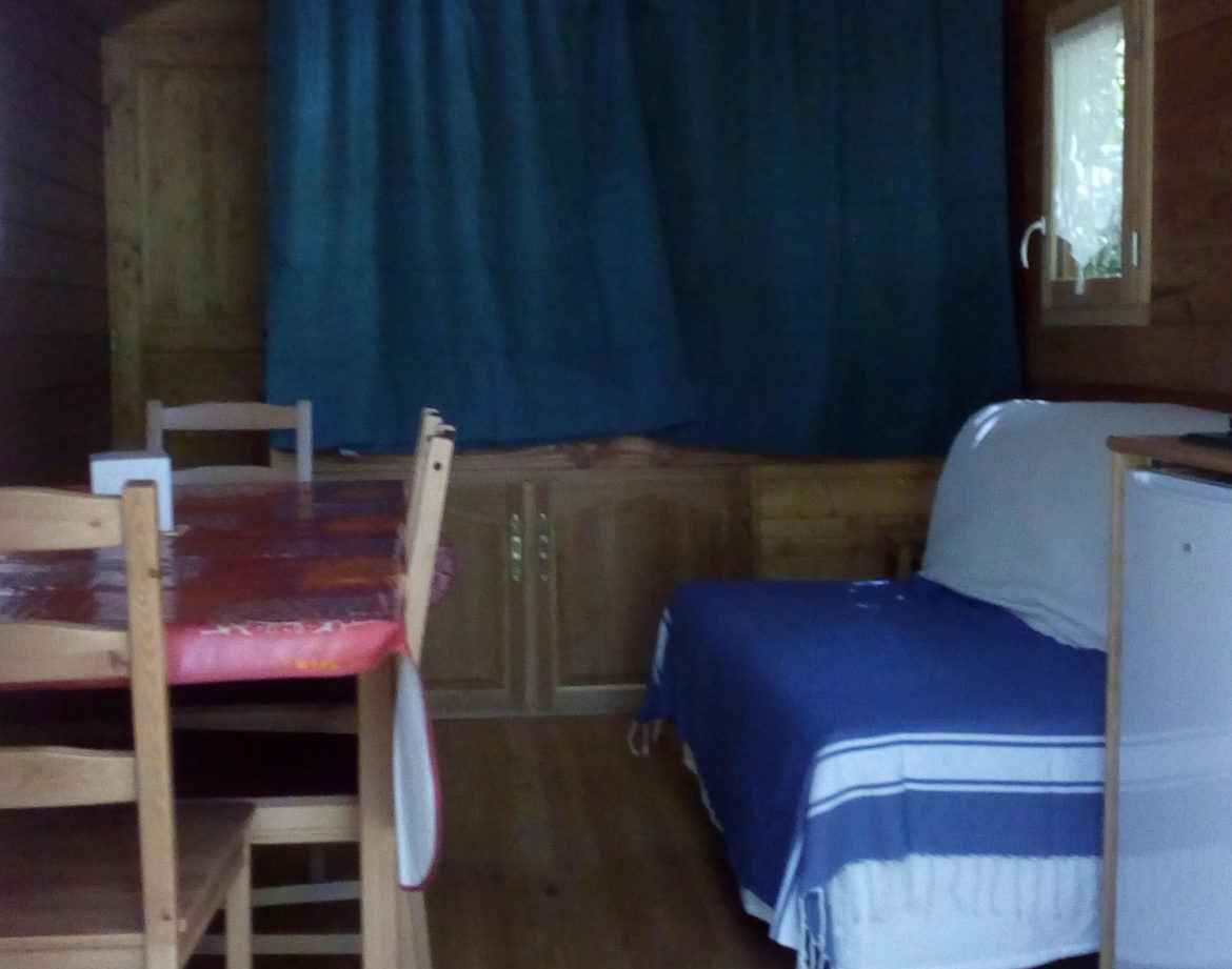 Hébergement insolite en bois avec un coin salon et une table à manger conviviale.