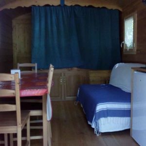 Hébergement insolite en bois avec un coin salon et une table à manger conviviale.