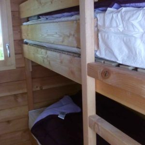 Chalet en bois avec lits superposés, ambiance chaleureuse et naturelle.