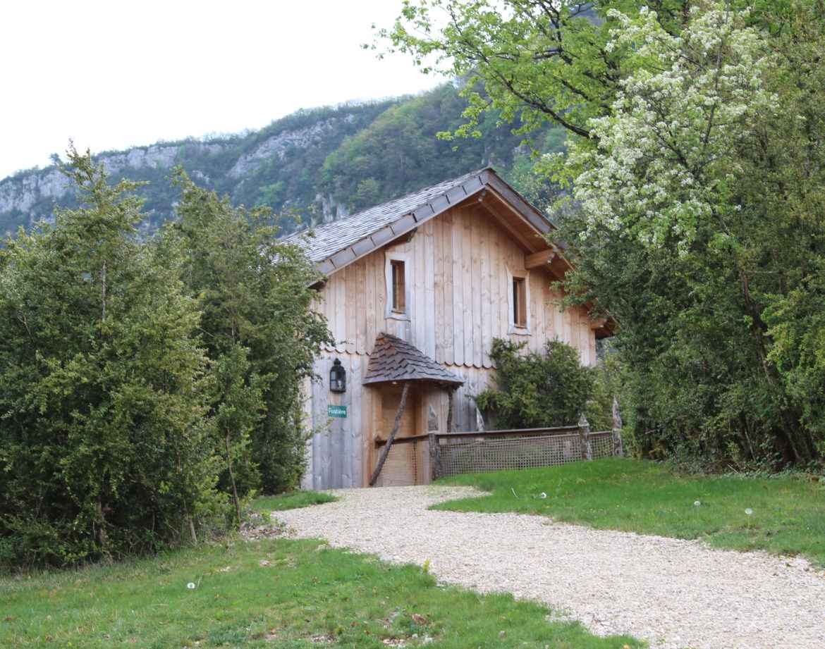 Chalet en bois niché dans la verdure, entouré de montagnes en Auvergne-Rhône-Alpes.