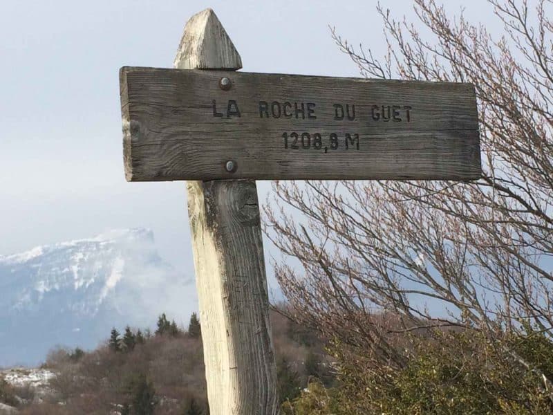 Auberge de montagne avec panneau indicatif et vue panoramique sur les sommets.
