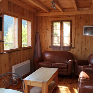 Cabane en bois cosy avec canapés en cuir et vue sur la nature en Auvergne-Rhône-Alpes.