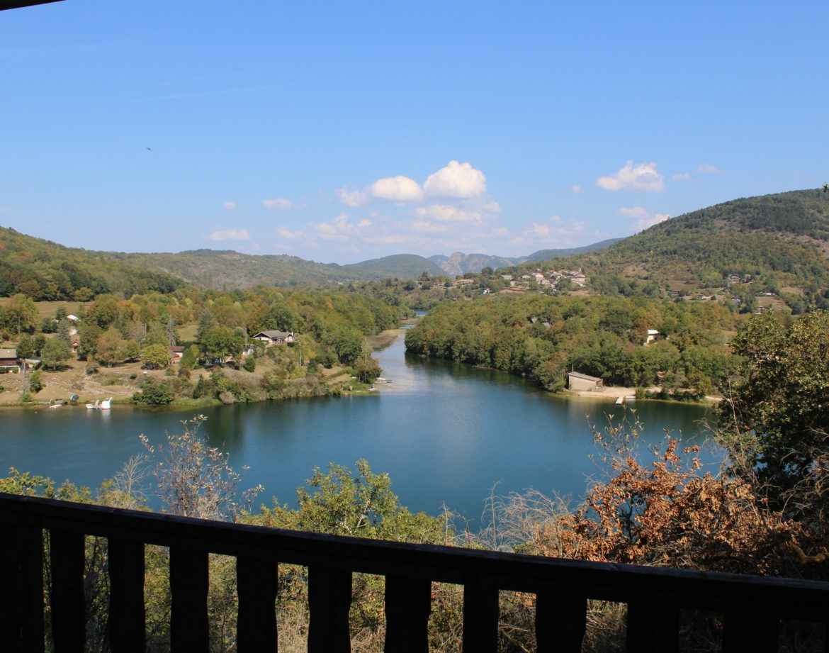 Cabane perchée avec vue panoramique sur la rivière et les collines verdoyantes.